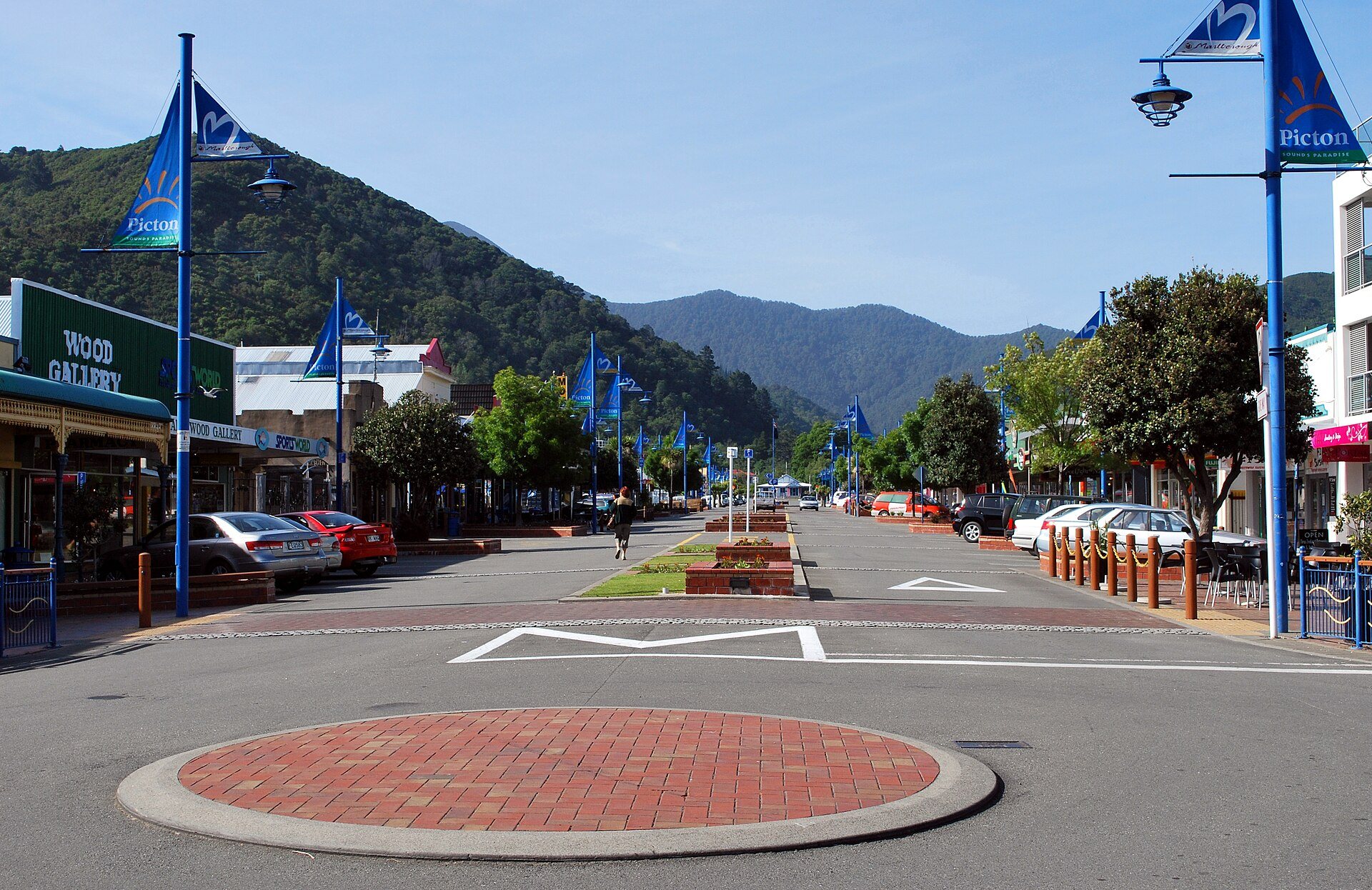 High Street, Picton's main street, lined with blue banners, shopfronts and parked cars, hills rising behind