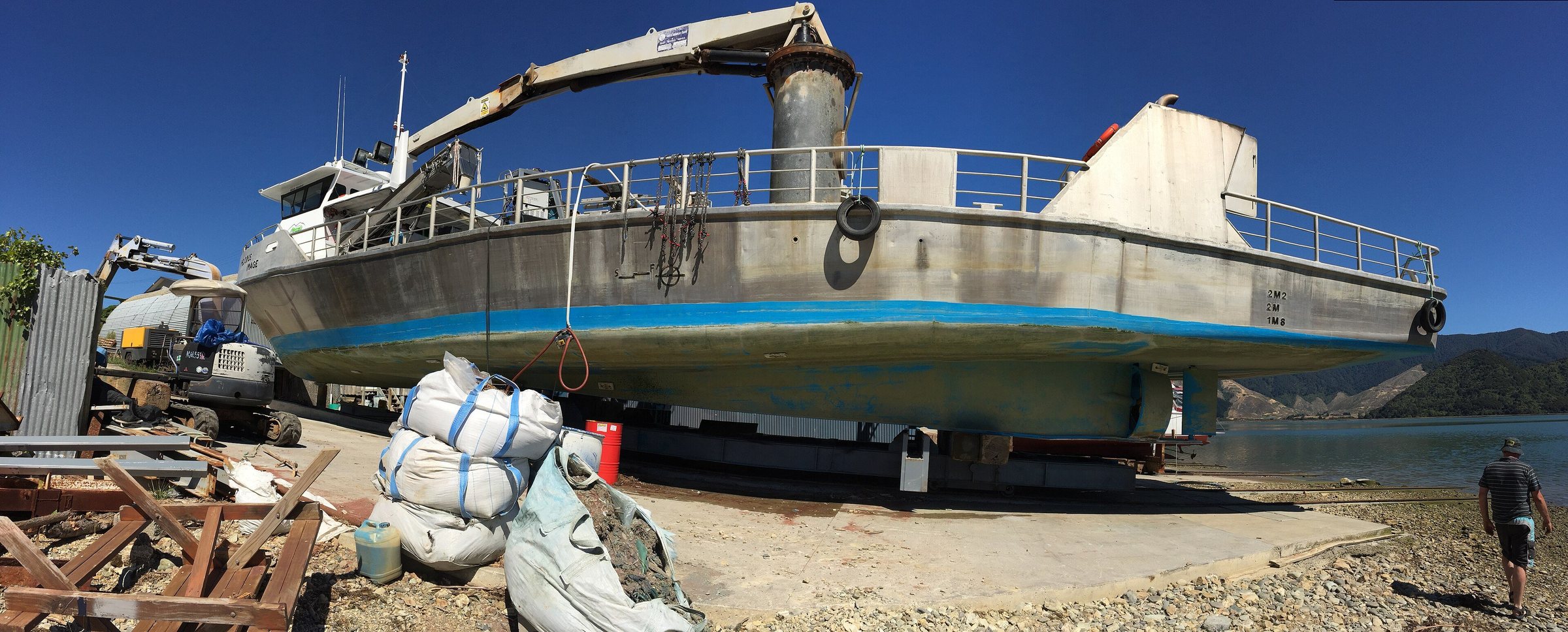A mussel barge hauled out on a slipway beside the water, with floats and gear stacked around it