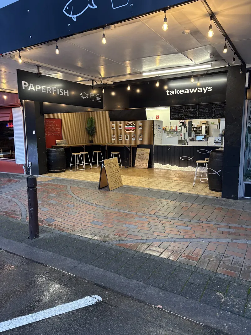 Open-front Paperfish takeaway on High Street, with branded signs, service counter and sheltered stools.