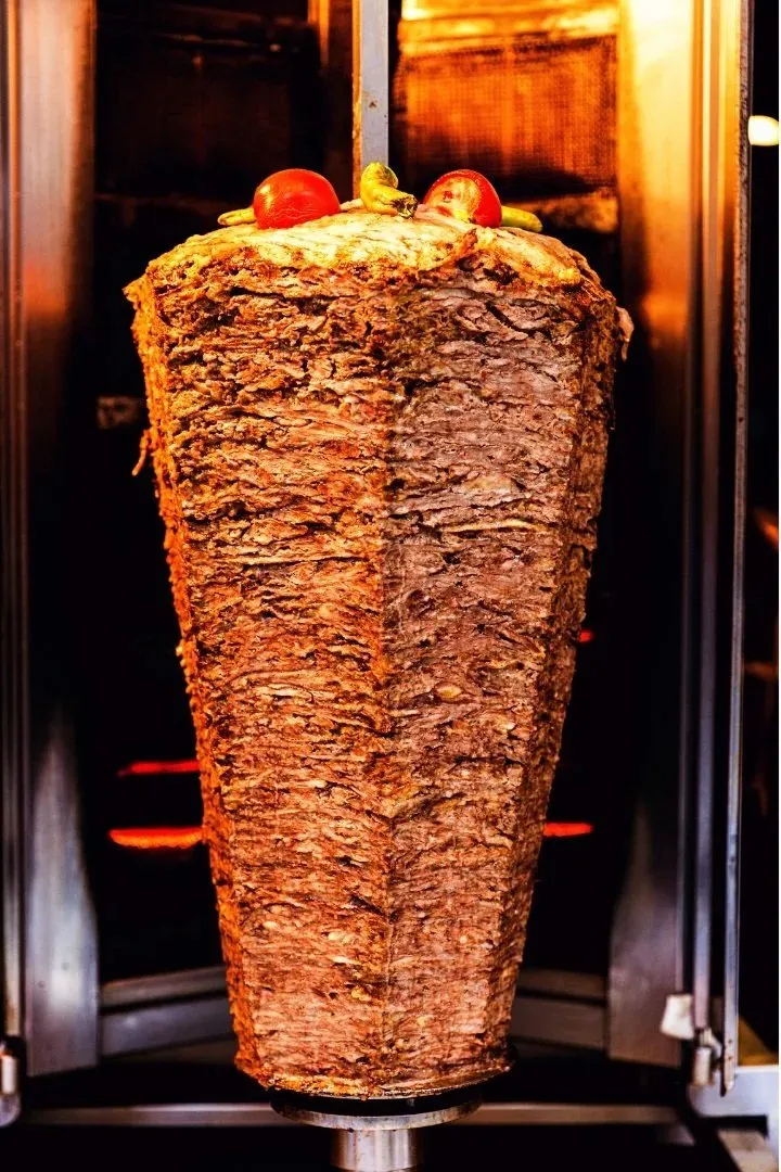 A large stack of kebab meat roasting vertically in the venue's rotisserie.