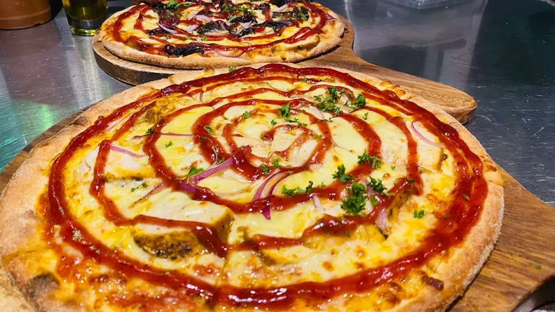 Two finished wood-fired pizzas on wooden serving boards in Scoozi's kitchen.
