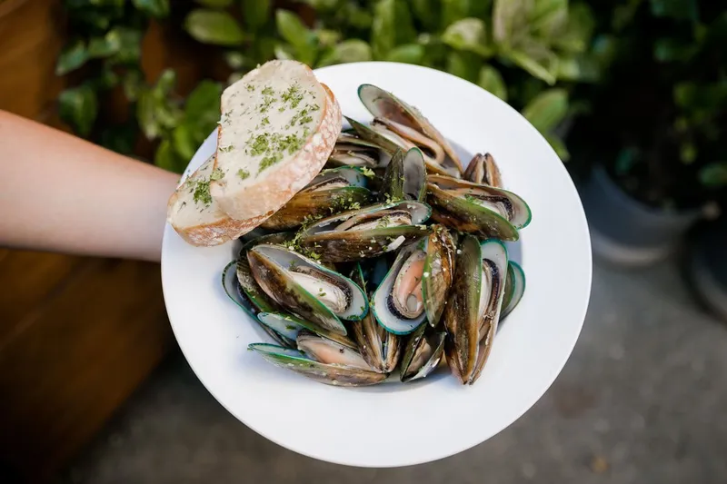 A bowl of New Zealand green-lipped mussels served with herb-topped bread.